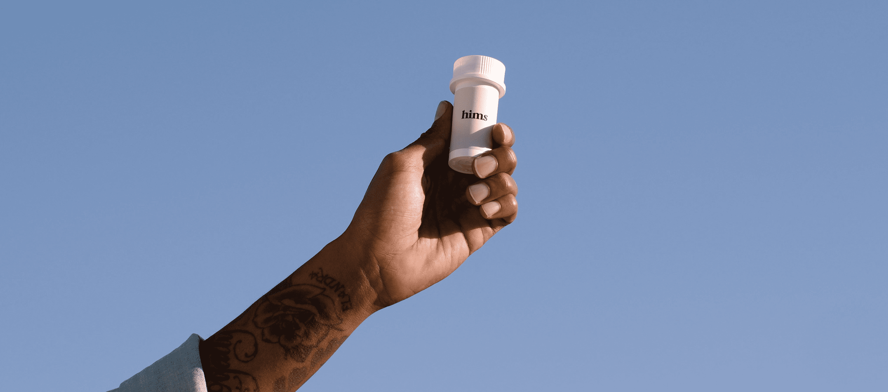 hand holding up hims pill bottle